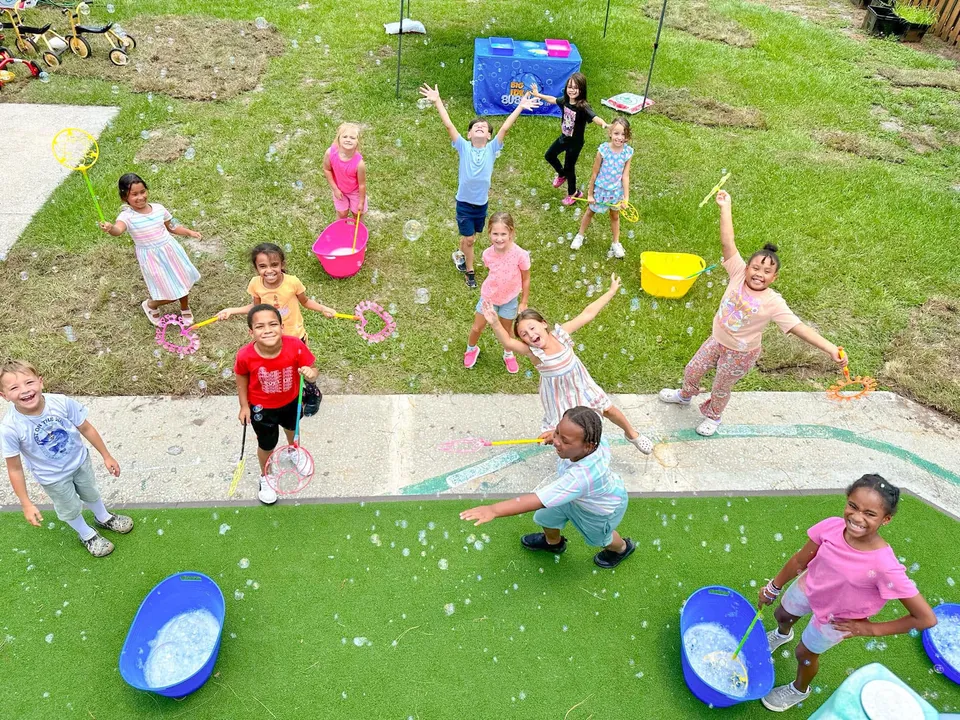A preschool group playing with bubbles on a lawn
