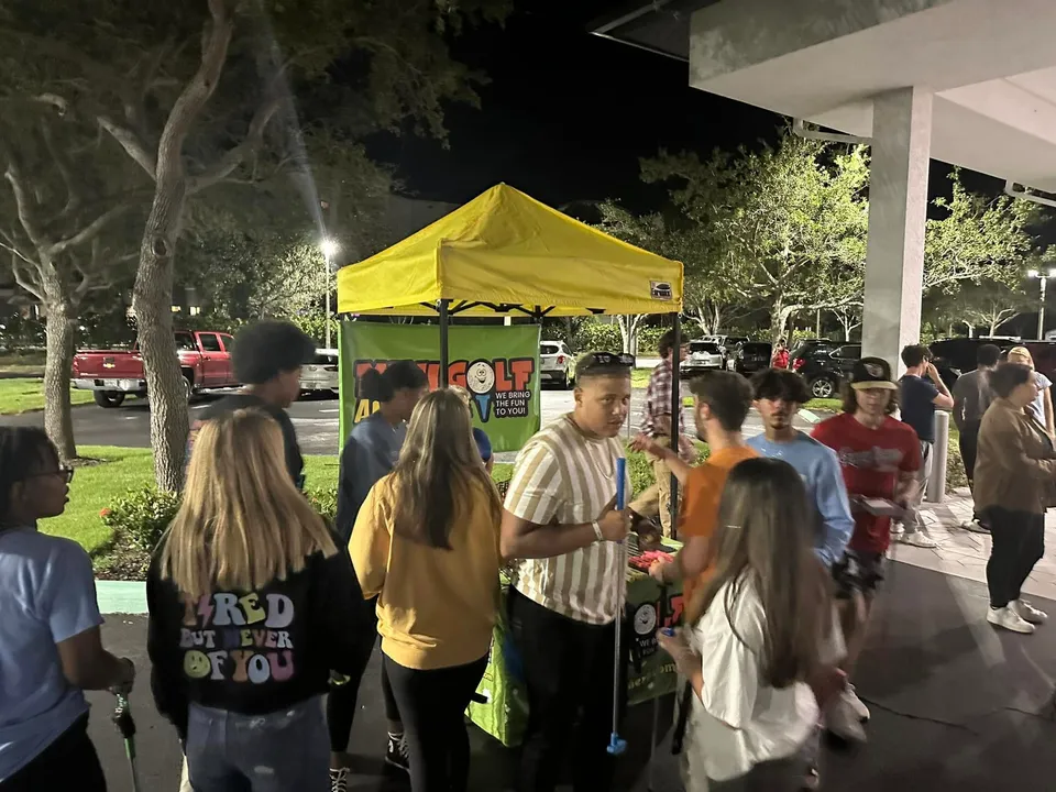 An evening event crowd gathered at a mini golf canopy