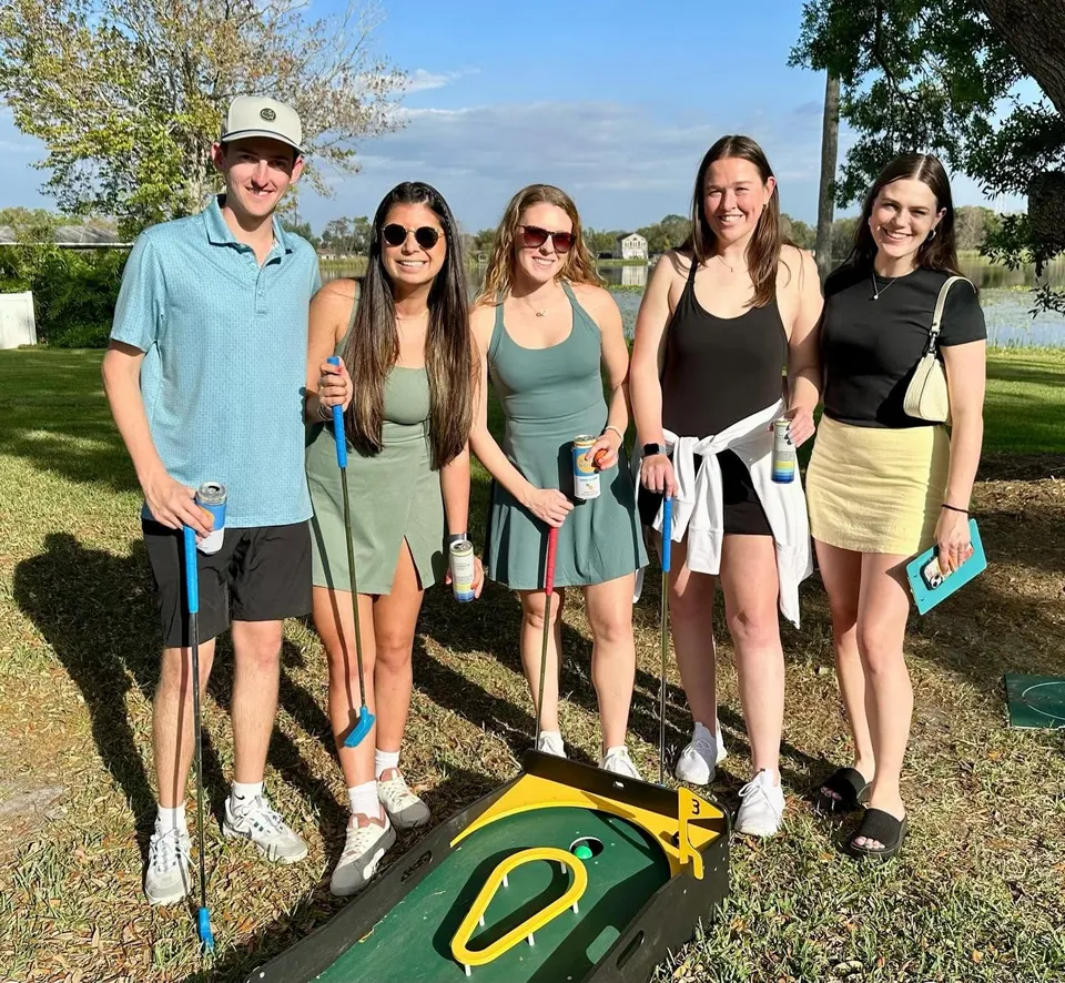 Adults play portable mini golf at an event