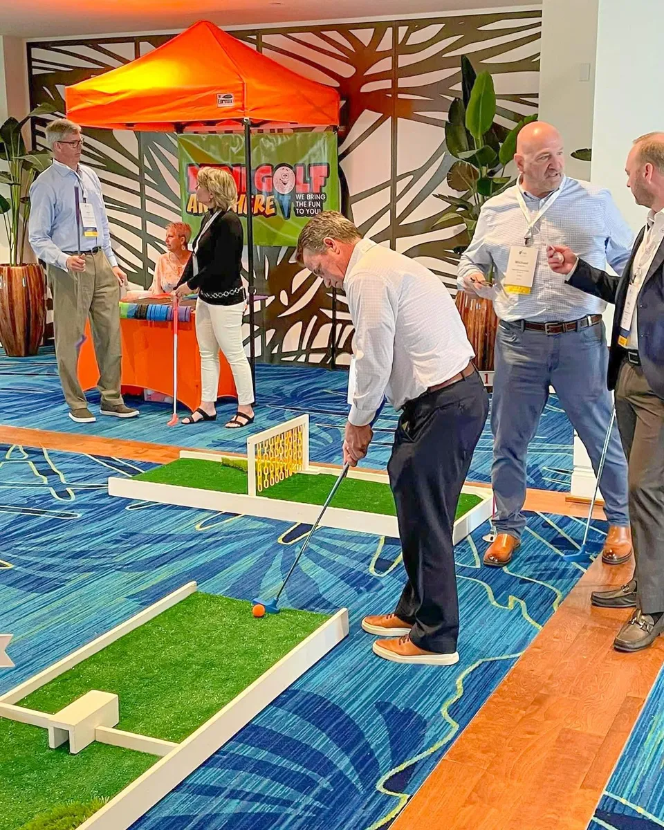 Adults playing portable mini golf indoors