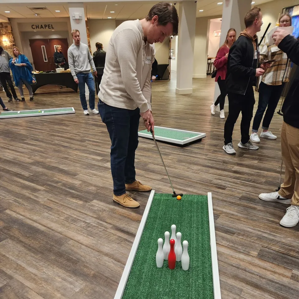 Adults play portable mini golf at an indoor venue event