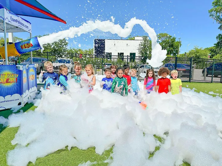A preschool group gathered around a foam cannon outdoors