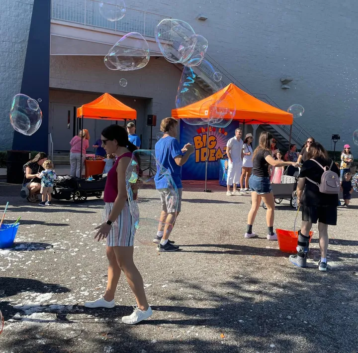 An outdoor community event under orange event tents